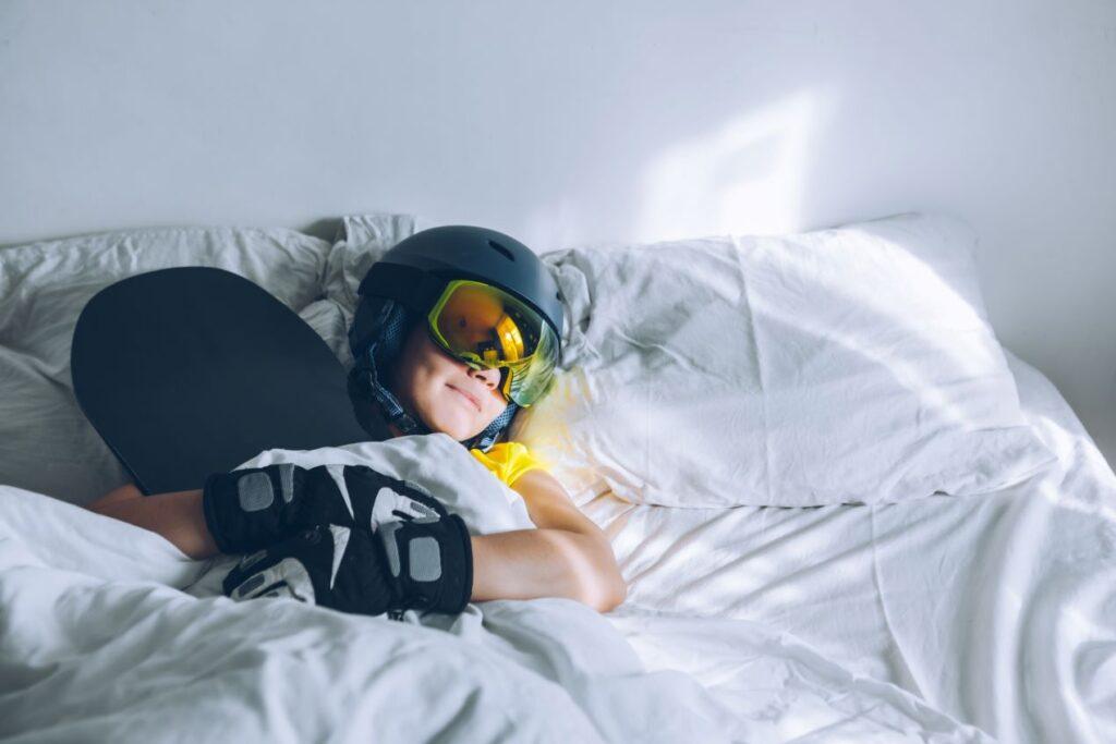 Sportler liegt in Trainingskleidung auf einem Bett mit Matratzentopper 140x200 und entspannt sich nach dem Workout