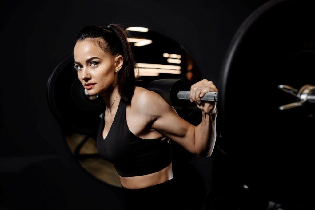 Frau beim Krafttraining mit Langhantel im Fitnessstudio, Personal Training in Koeln